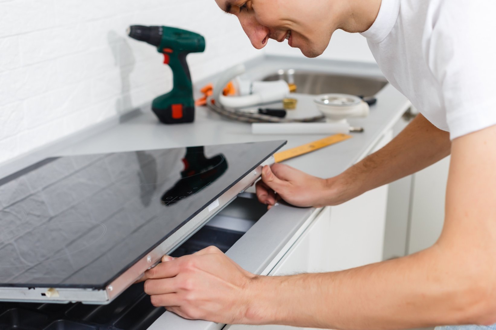 Young repairman installing induction cooker in kitchen