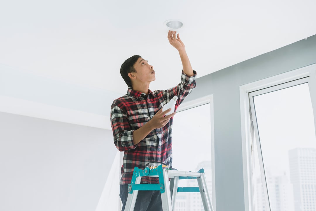 Handyman Installing a Light Bulb on the Ceiling